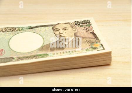 Ten thousand yen (10,000 yen) banknotes stacked. Japanese money. Paper money. isolated on wooden table. Side view. Stock Photo