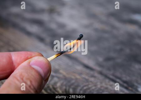 Men's fingers hold a burning match on a blurred background close-up. Stock Photo