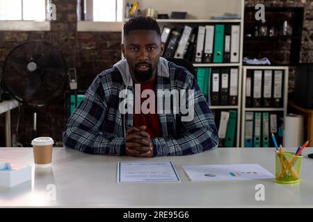 African american businessman sitting at desk, having video call and talking in office Stock Photo