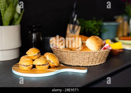 Close up of basket with rolls and mini hamburgers on countertop in kitchen Stock Photo