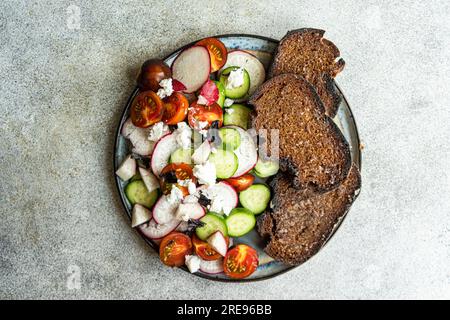 From above vegetable salad in Greek style with feta cheese on concrete background Stock Photo