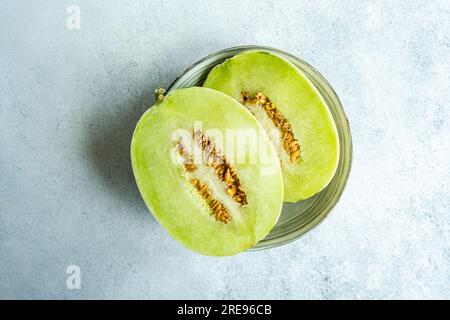 Top view melon split in half placed in a bowl on concrete background Stock Photo
