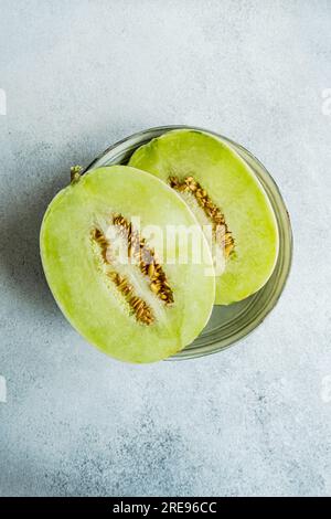 Top view melon split in half placed in a bowl on concrete background Stock Photo