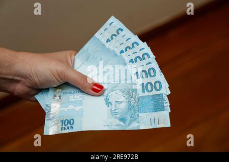 several hundred real bills - money from Brazil in a womans hand with red nails Stock Photo