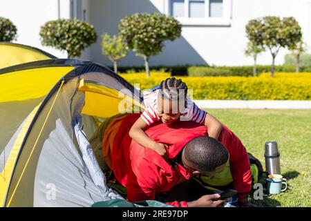 Happy african american son and father playing in tent sunny garden Stock Photo