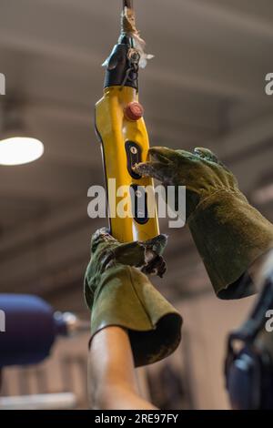 Side view of anonymous crop worker in protective gloves working in factory and reaching button on switch board Stock Photo