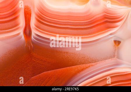 Closeup of cross section of agate crystal from Malawi with fine textured background with distinct vibrant orange and violet color wavy lines with tiny Stock Photo