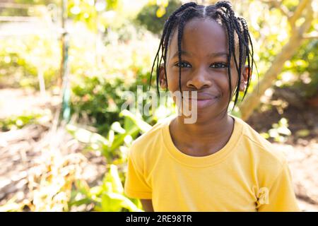 Portrait of happy african american boy wearing yellow t-shirt, smiling in garden Stock Photo