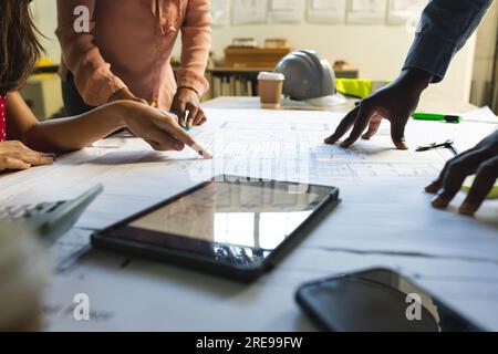 Diverse colleagues discussing work with tablet over project of building in office Stock Photo