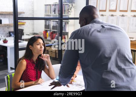 Diverse colleagues discussing work over project of building in office Stock Photo
