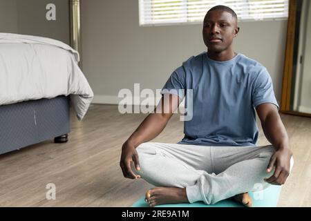 African american man doing yoga and meditating at home Stock