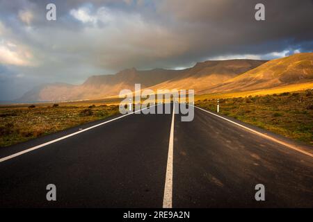 a scenic road goes straight to el Risco de Famara during the golden hour Stock Photo