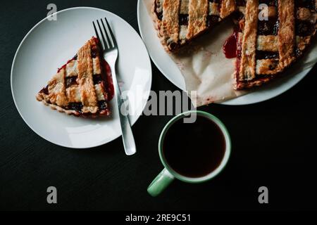 Cherry pie with a cup of regular coffee on black table Stock Photo