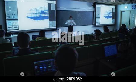 Young Female Teacher Giving a Data Science Lecture to Diverse Multiethnic Group of Female and Male Students in Dark College Room. Projecting Slideshow Stock Photo