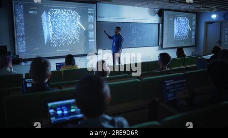 Young Male Teacher Giving a Data Science Lecture to a Diverse Multiethnic Group of Female and Male Students in a Dark College Space. Projecting Slides Stock Photo