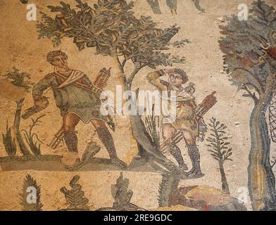 Mosaic in the Room of the Small Hunt, Villa Romana del Casale, Sicily depicts two men hunting thrushes with falcons. Stock Photo