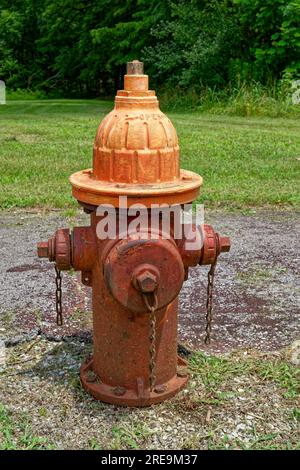 Grungy old fire hydrant alongside a path by the road with peeling and faded paint bolted to the ground still operational outdoors on a sunny day in su Stock Photo