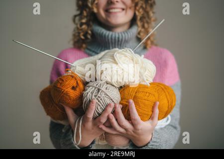Woman's hands holding many skeins of yarn for knitting, knitting needles. Craft and DIY. Stock Photo