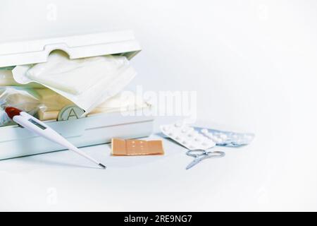 Part of a first aid kit for the car and home medicine chest with bandages, plasters, fever thermometer, pills and scissors, health and medical concept Stock Photo