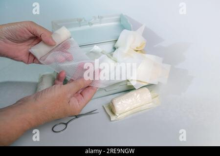 Hands of an older woman taking a sterile gauze bandage out of a first aid kit with medical supplies, health and medicine concept, copy space, selected Stock Photo