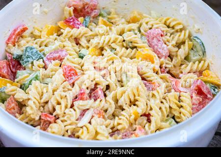 Pasta salad with bell pepper, zucchini and mayonnaise in a plastic bowl to bring along for a garden party, selected focus, narrow depth of field Stock Photo