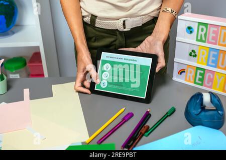 Teacher showing tablet with tips to be more ecological in environmental classroom Stock Photo