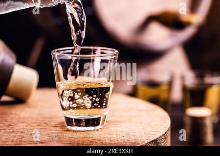 Glass of golden rum, with bottle. Bottle pouring alcohol into a small glass. Brazilian export type drink. Brazilian product for export, distilled drin Stock Photo
