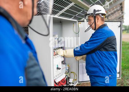 Two Service Engineers or electrician working on checking transformer site and solving problem for green energy solar power plant operation. Technician Stock Photo