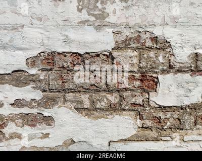 Texture of old brick wall with collapsed plaster. Background of shabby building surface. Destroyed stone wall with fallen plaster. Weathered surface. Stock Photo