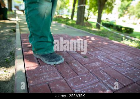 A worker in working clothes is standing on a cobblestone pavement. Stock Photo