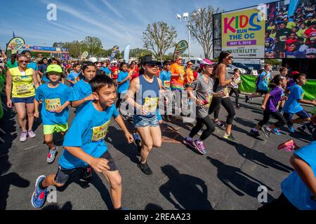 Costa Mesa, California, USA. 5th May, 2018. 10-year-old multiracial runners pass a Jumbotron video image of themselves as the race begins at a community track event in Costa Mesa, CA. (Credit Image: © Spencer Grant/ZUMA Press Wire) EDITORIAL USAGE ONLY! Not for Commercial USAGE! Stock Photo