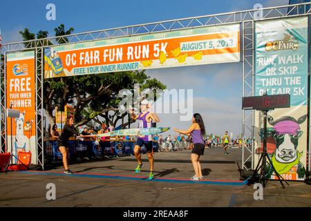 Costa Mesa, California, USA. 5th Aug, 2018. The winner of a county fair 5K ''Fun Run'' breaks the finish line tape in Costa Mesa, CA. (Credit Image: © Spencer Grant/ZUMA Press Wire) EDITORIAL USAGE ONLY! Not for Commercial USAGE! Stock Photo