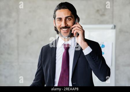 Smiling handsome businessman talking on phone at office Stock Photo