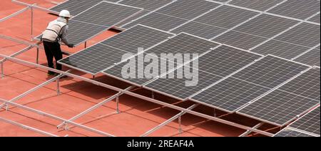 Worker installing solar panels on roof terrace Stock Photo