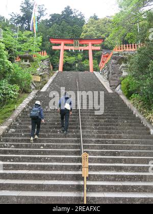 A flight of steep stone steps leads to a red Torii Gate at the entrance to the Nachi Taisha Shinto Shrine, one of the Three Grand Shrines of Kumano. Stock Photo
