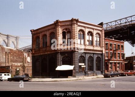AJAXNETPHOTO. JULY, 1975. BROOKLYN, NEW YORK, USA. - OLD BANK - BROOKLYN BRIDGE TOWER EMERGING BEHIND NINETEENTH CENTURY COMMERCIAL BUILDINGS ON THE CORNER OF FRONT STREET AND CADMAN PLAZA WEST; THE OLD FULTON FERRY BANK AND TO ITS LEFT, THE OLDEST REMAINING 19TH CENTURY COMMERCIAL BUILDING BELOW THE DECK OF THE BROOKLYN BRIDGE SPANNING EAST RIVER BETWEEN PARK ROW MANHATTAN AND SANDS STREET, BROOKLYN, NEW YORK CiTY.  PHOTO:JONATHAN EASTLAND/AJAXREF:601874 138 2 Stock Photo