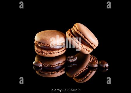 Flavoured coloured macarons on a reflective surface with coffee beans Stock Photo