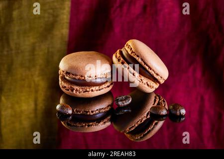 Flavoured coloured macarons on a reflective surface with coffee beans Stock Photo