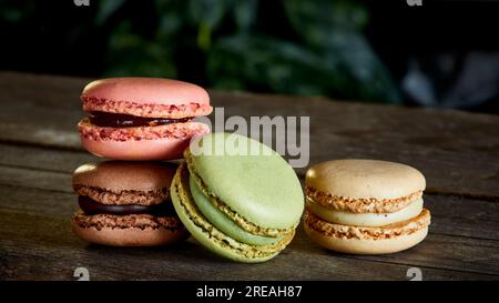 Stack of flavoured coloured macarons on a rough wooden surface Stock Photo