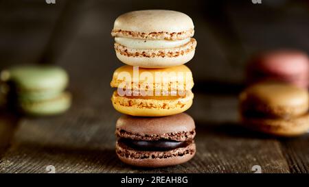 Stack of flavoured coloured macarons on a rough wooden surface Stock Photo