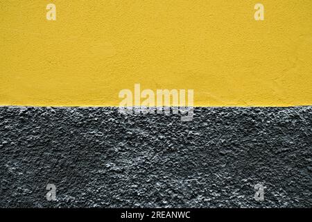 Empty two color background in subdued yellow and black colors - a freshly painted exterior wall. Stock Photo