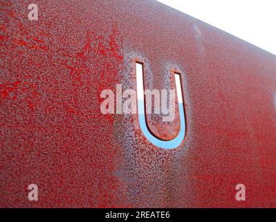 Single capital letter U cut out in rusty metal plate, angled perspective view. Stock Photo