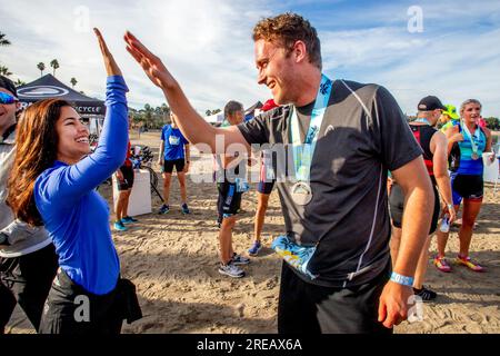 Newport Beach, California, USA. 4th Nov, 2018. Wearing a finishing medallion, a triathlete gets high five congratulations at the finish line of a triathlon competition in Newport Beach, CA. (Credit Image: © Spencer Grant/ZUMA Press Wire) EDITORIAL USAGE ONLY! Not for Commercial USAGE! Stock Photo