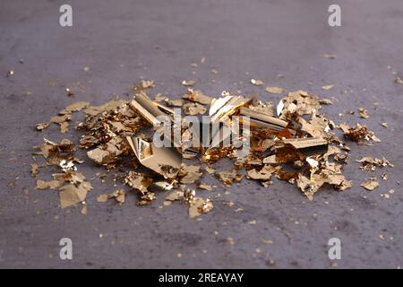 Many pieces of edible gold leaf on grey textured table, closeup Stock Photo