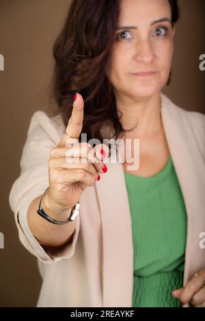 Portrait smiling and confident coaching woman making hand gestures. Motivational and democratic management. Isolated on brown background. Stock Photo