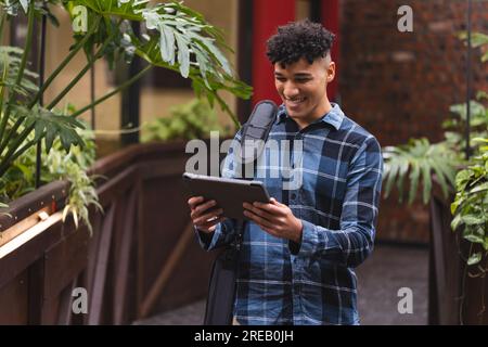 Biracial man smiling while using a digital tablet at office Stock Photo