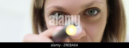 Doctor anesthesiologist resuscitator shining medical flashlight into patient eyes closeup Stock Photo