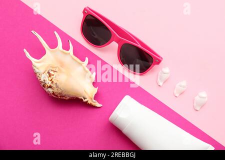 Composition with sunglasses, seashells and sunscreen on pink background Stock Photo
