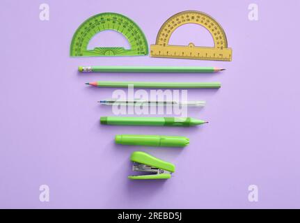 Different school stationery in shape of heart on purple background Stock Photo