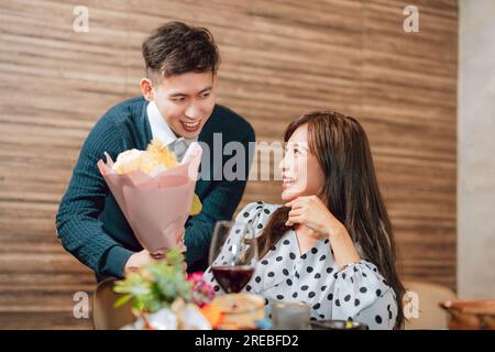 Young man greeting his girlfriend on Valentine's Day at restaurant Stock Photo